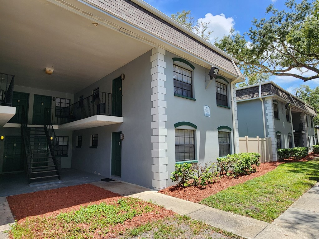 the front of a white house with a yard and a staircase at Greenwich Commons Apartment Homes, Tampa, FL