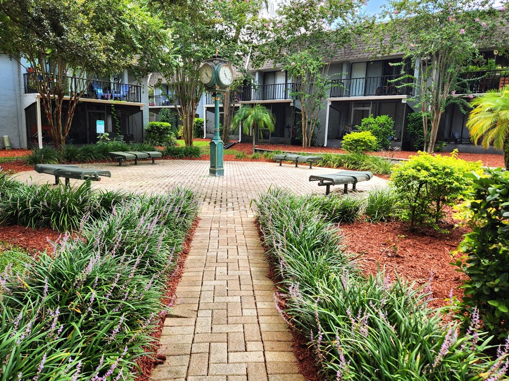 a courtyard with benches and a clock at Greenwich Commons Apartment Homes, Florida