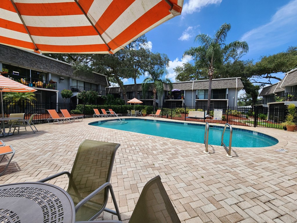 a swimming pool with chairs and an umbrella at a hotel at Greenwich Commons Apartment Homes, Florida