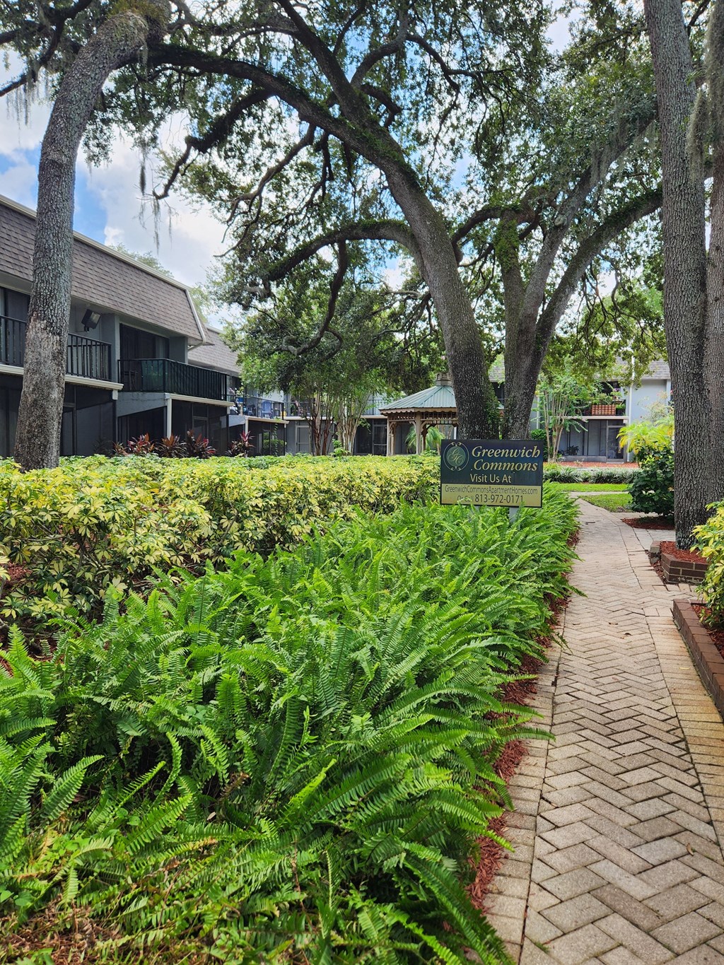 a sidewalk in front of a building with a sign at Greenwich Commons Apartment Homes, Florida, 33613