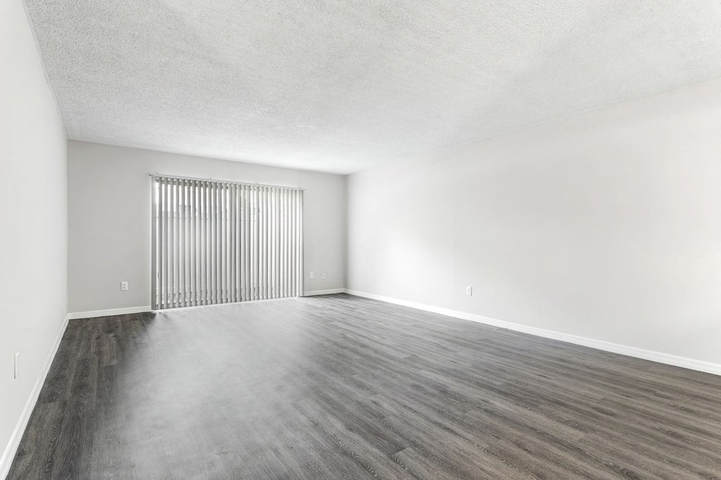 an empty living room with white walls and wood floors at Greenwich Commons Apartment Homes, Florida