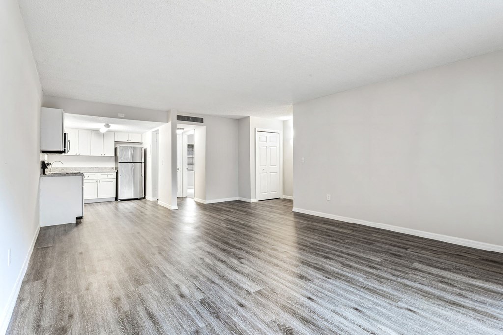 an empty living room and kitchen with white walls and wood floors an empty living room and kitchen with white walls and wood floors at Greenwich Commons Apartment Homes, Tampa, FL, 33613