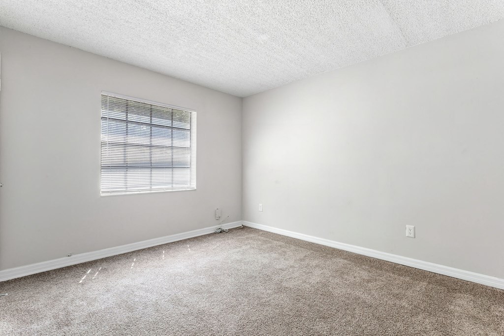an empty room with carpet and a window at Greenwich Commons Apartment Homes, Tampa, Florida