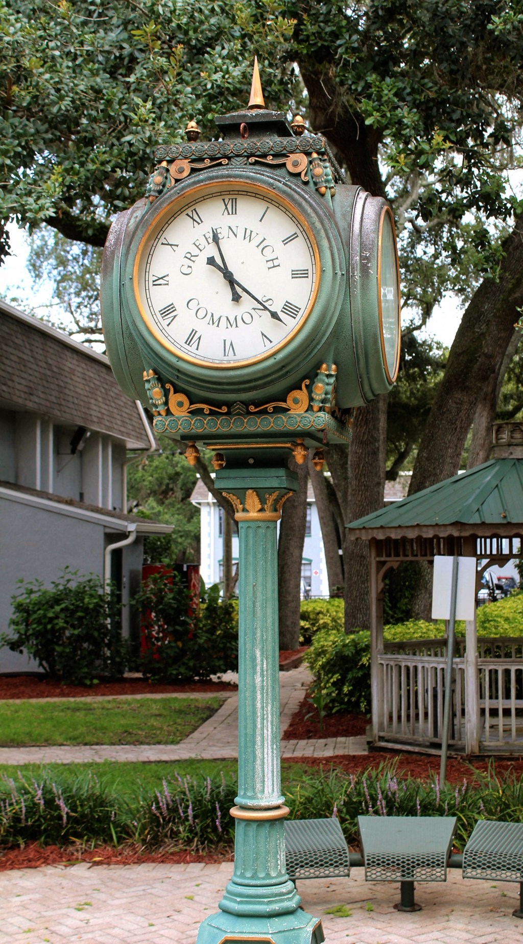 a green clock on a pole in a park at Greenwich Commons Apartment Homes, Tampa, Florida