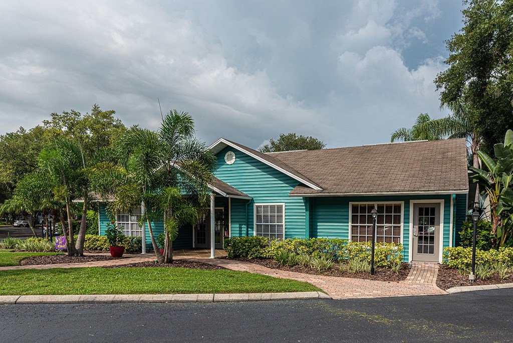 a blue house with palm trees in front of it at Madison Oaks Apartment Homes, LLC, Palm Harbor Florida