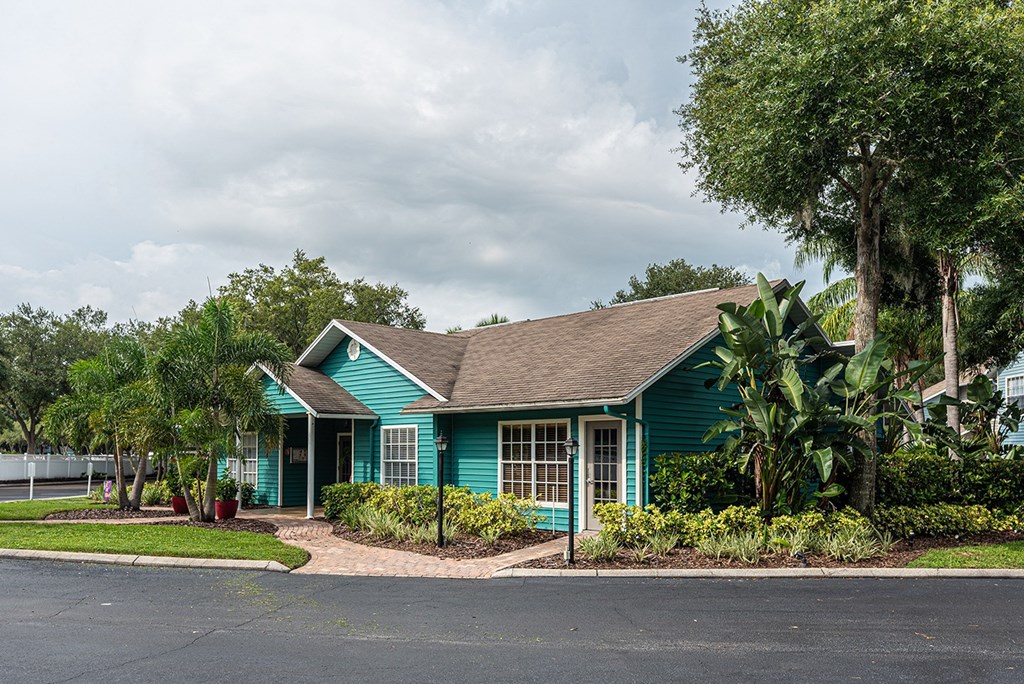 a green house with trees and a road in front of it at Madison Oaks Apartment Homes, LLC, Palm Harbor, FL 34684