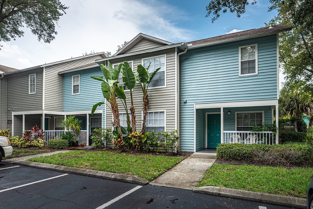 a blue house with palm trees in front of it at Madison Oaks Apartment Homes, LLC, Palm Harbor
