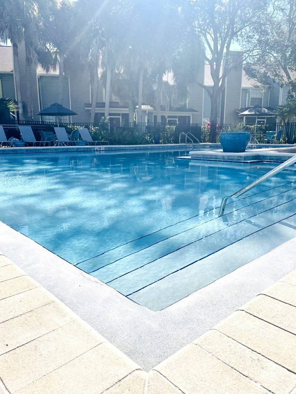 a swimming pool with a bunch of chairs in it at Madison Oaks Apartment Homes, LLC, Palm Harbor, FL 34684