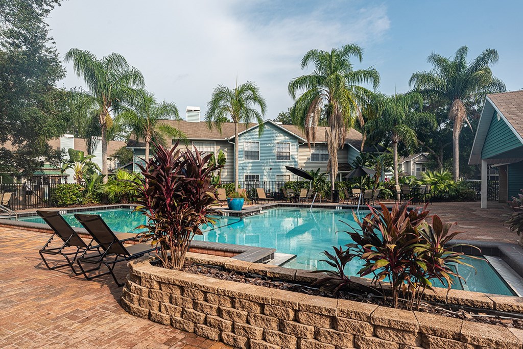 a swimming pool with palm trees in front of a house at Madison Oaks Apartment Homes, LLC, Florida, 34684