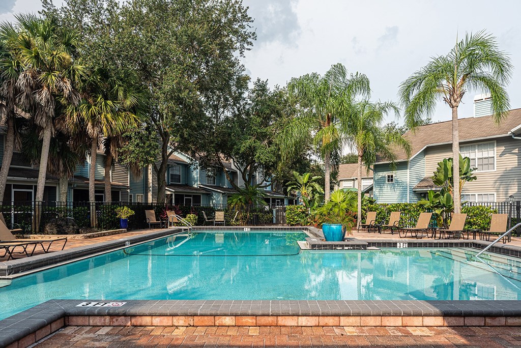 a swimming pool with palm trees in front of apartment buildings at Madison Oaks Apartment Homes, LLC, Florida