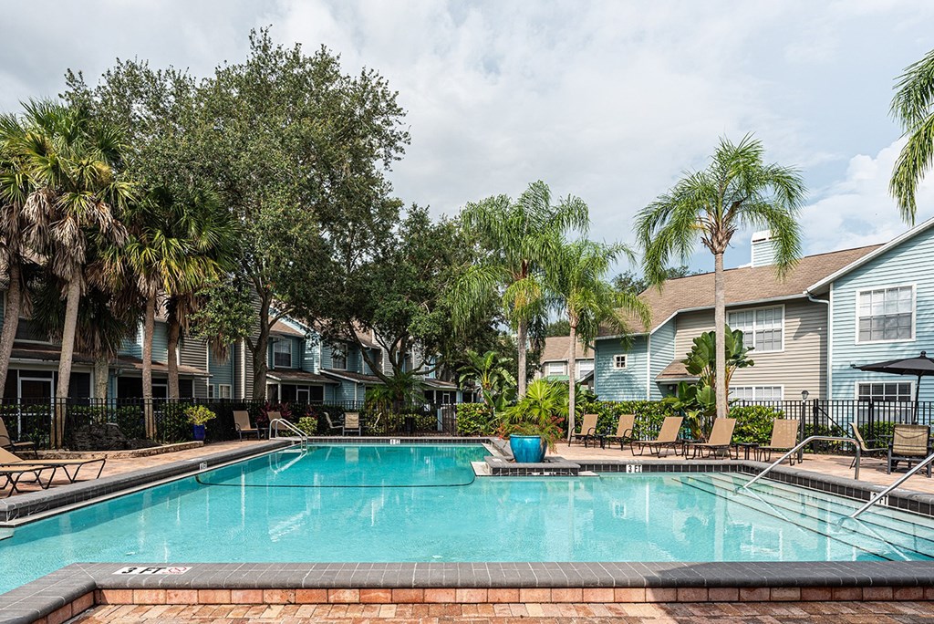 a swimming pool with palm trees in front of apartment buildings at Madison Oaks Apartment Homes, LLC, Palm Harbor, FL
