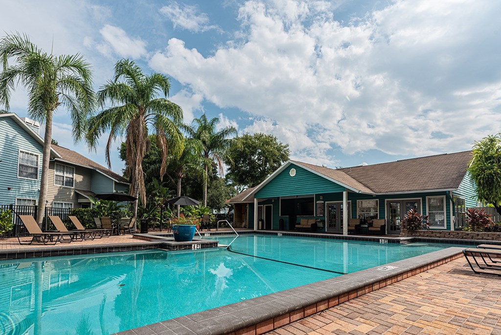 a large swimming pool with a house in the background at Madison Oaks Apartment Homes, LLC, Palm Harbor, FL 34684
