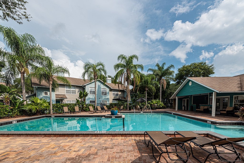 a swimming pool with chairs and houses in the background at Madison Oaks Apartment Homes, LLC, Florida