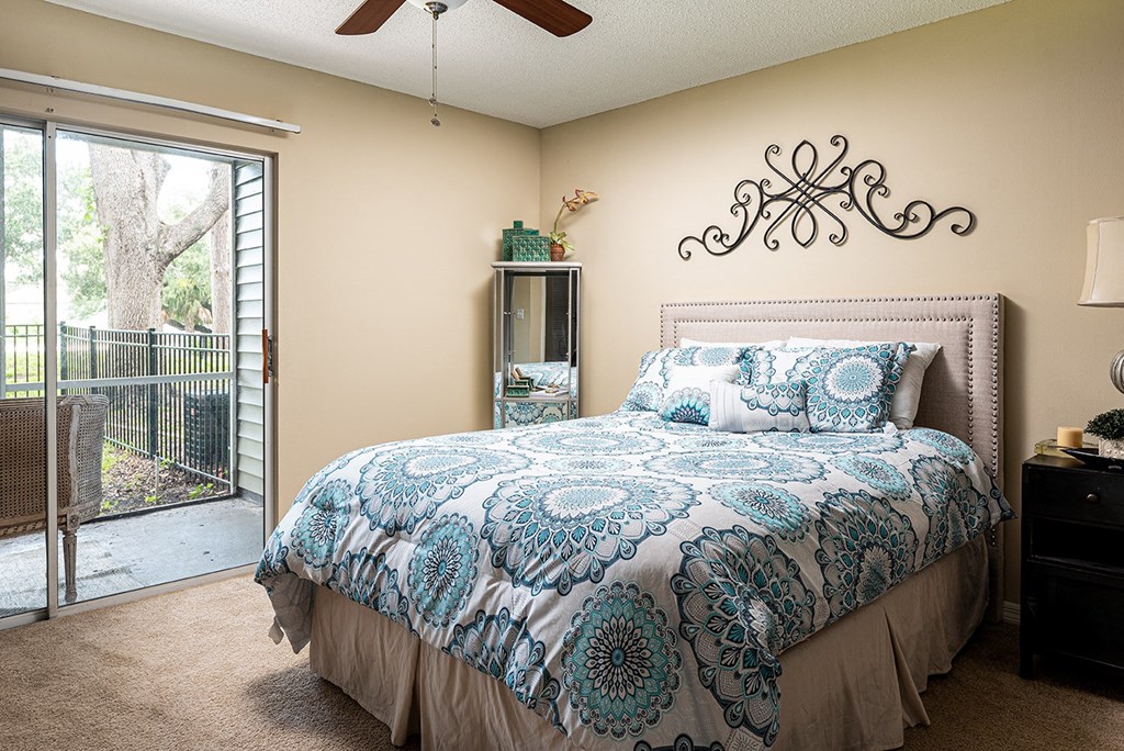 a bedroom with a bed and a sliding glass door at Madison Oaks Apartment Homes, LLC, Palm Harbor, FL 34684