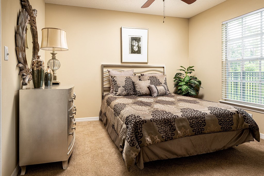 a bedroom with a bed and a dresser and a window a bedroom with a bed and a dresser and a window at Madison Oaks Apartment Homes, LLC, Palm Harbor Florida