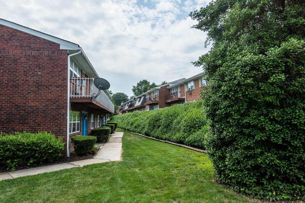 a row of brick apartment buildings with grass and bushes at Raritan Crossing Apartment Homes, New Jersey