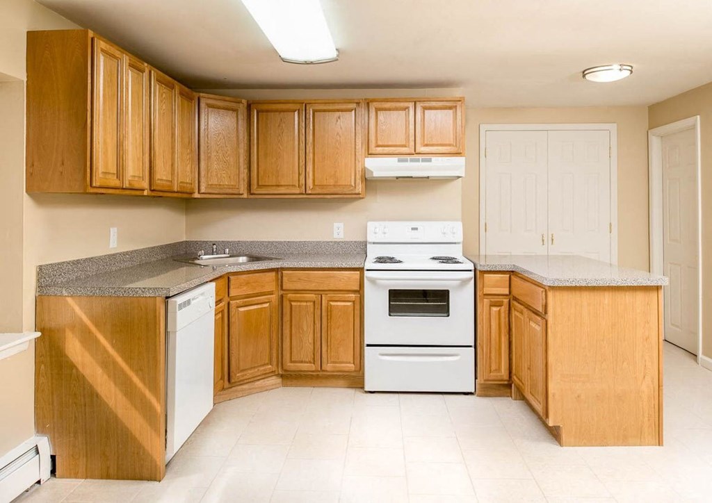 a kitchen with white appliances and wooden cabinets at Raritan Crossing Apartment Homes, New Jersey