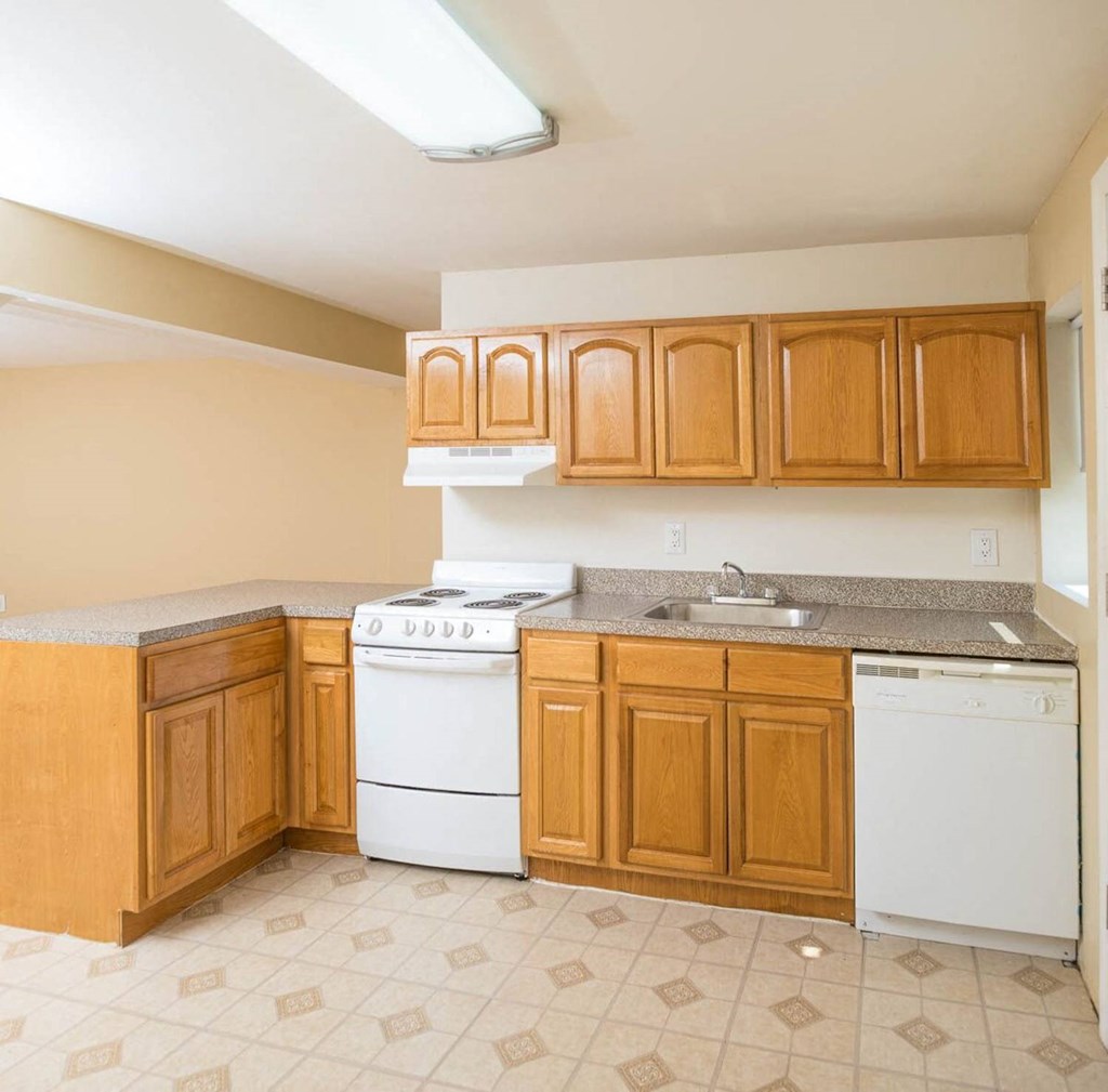 a kitchen with white appliances and wooden cabinets at Raritan Crossing Apartment Homes, New Brunswick New Jersey