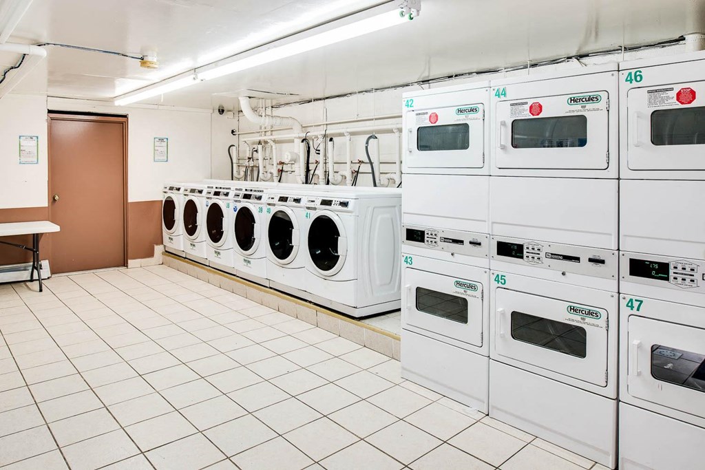 a row of white washing machines in a laundry room at Raritan Crossing Apartment Homes, New Brunswick, NJ