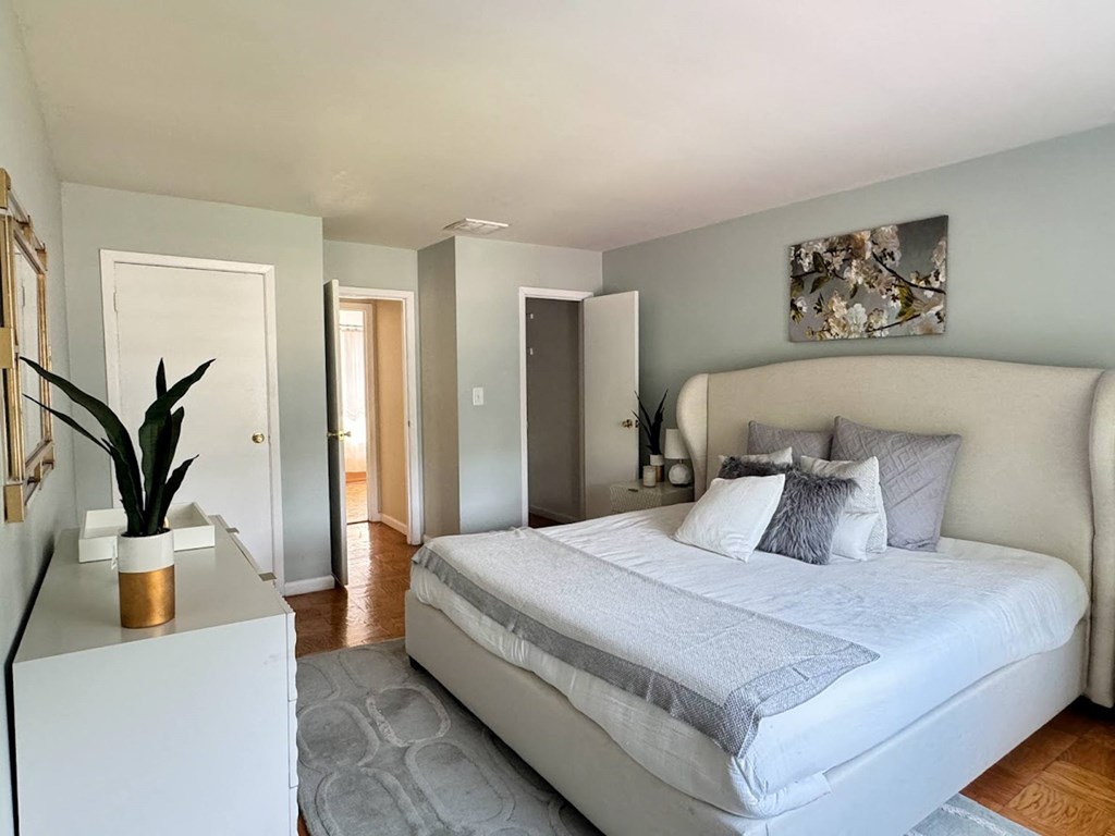 a bedroom with a large bed and a white dresser at Raritan Crossing Apartment Homes, New Brunswick, NJ 08901