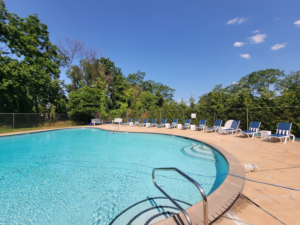 a swimming pool with chairs and trees in the background at Raritan Crossing Apartment Homes, New Brunswick, 08901