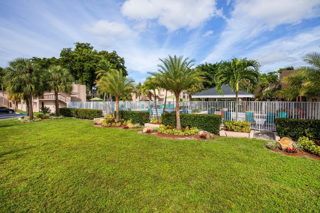 A well-maintained lawn with a fence and trees in the background.