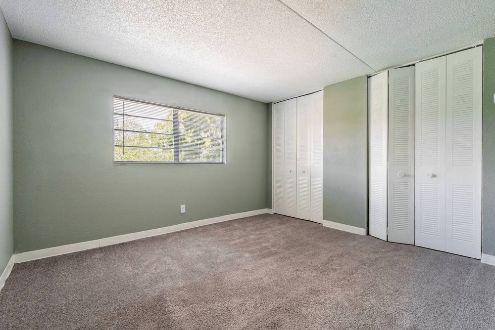 a bedroom with two closets and a carpeted floor at Bella Mar Apartments