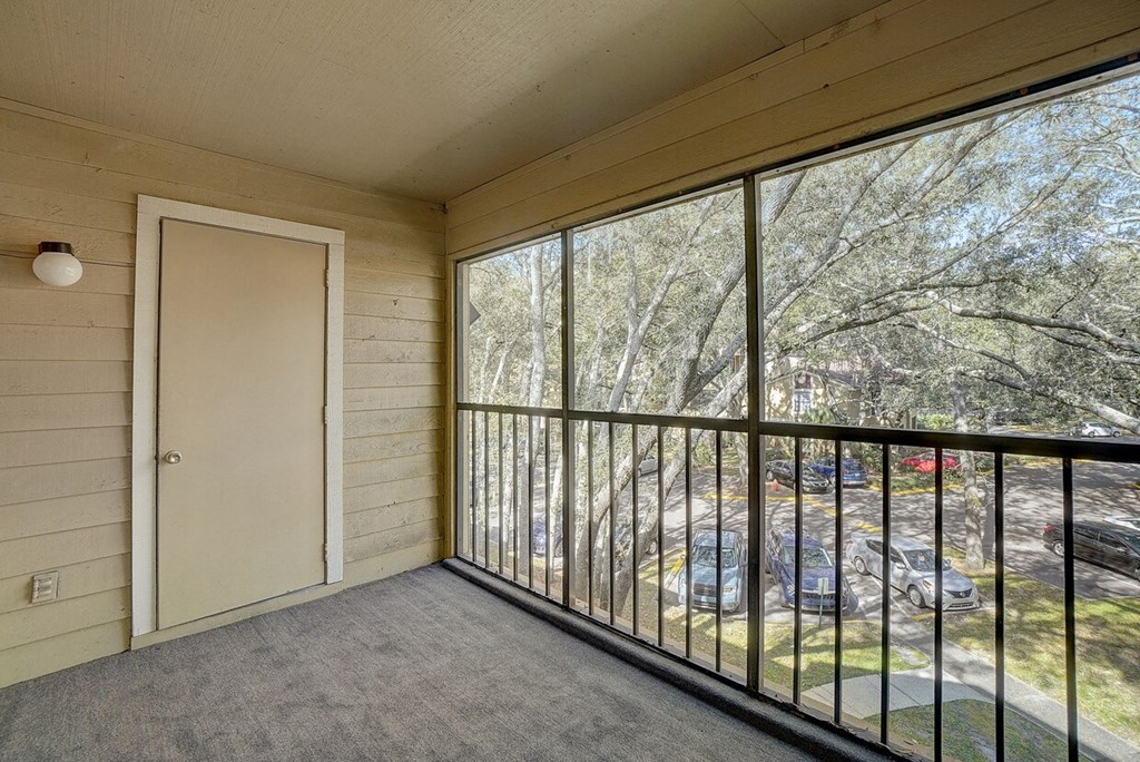 A balcony with a view of a parking lot and trees.
