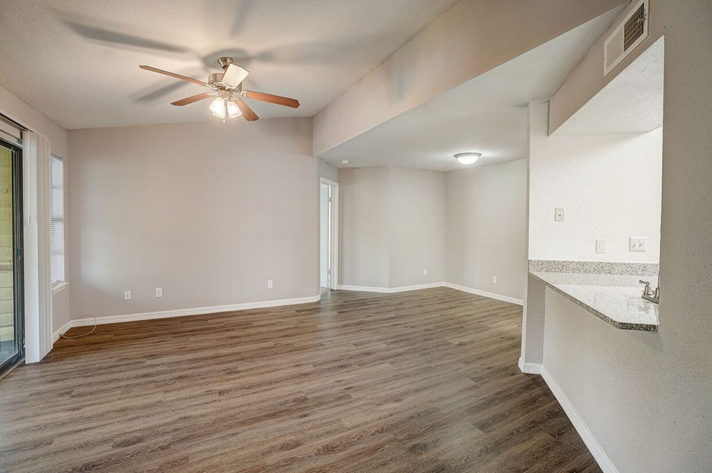 A room with a ceiling fan and wooden flooring.