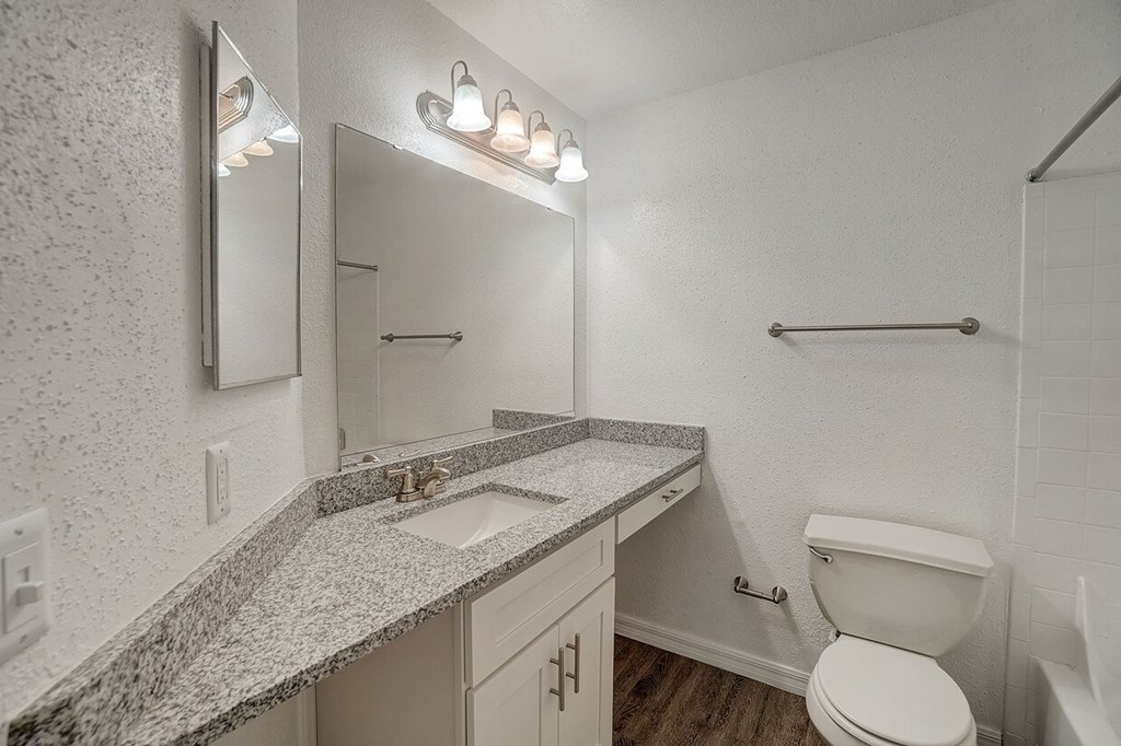 A bathroom with a granite countertop and white walls.