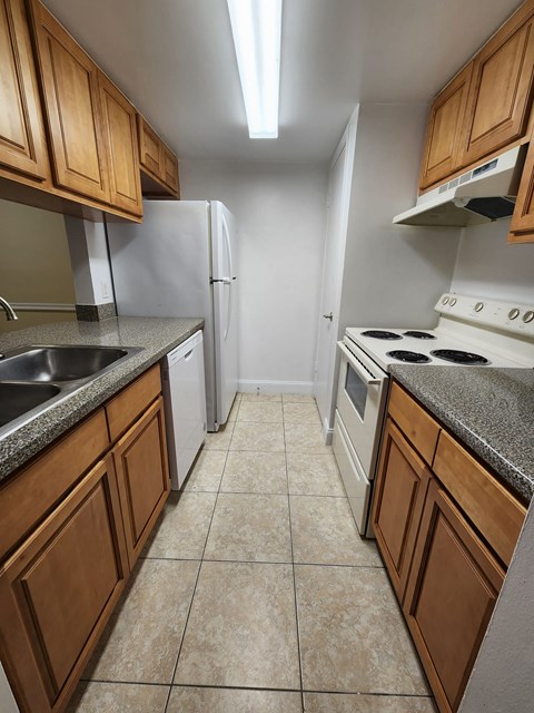 a kitchen with white appliances and wooden cabinets at Sunscape Apartment Homes, Tampa, 33613