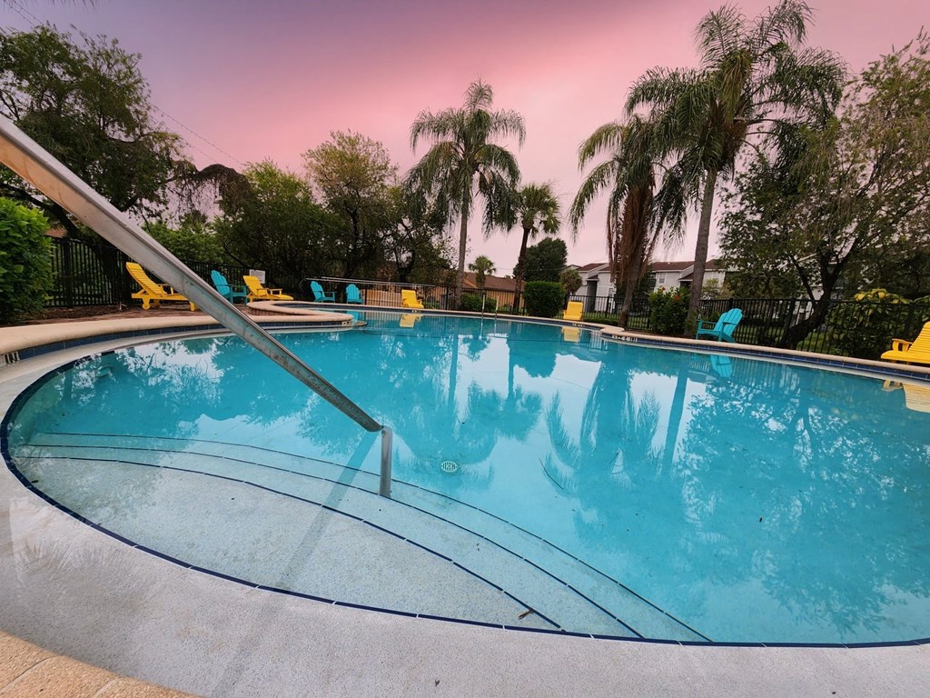 a swimming pool with palm trees and chairs around it at Sunscape Apartment Homes, Tampa, FL, 33613