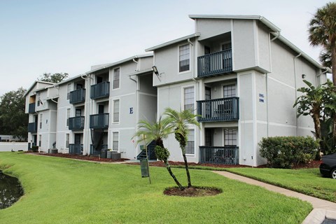 an exterior view of an apartment building with palm trees at Sunscape Apartment Homes, Tampa