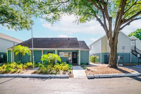 A small building with a green roof is surrounded by trees and plants.