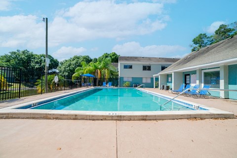 A swimming pool in front of a building with a fence around it.