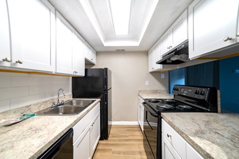 A kitchen with black appliances and white cabinets.