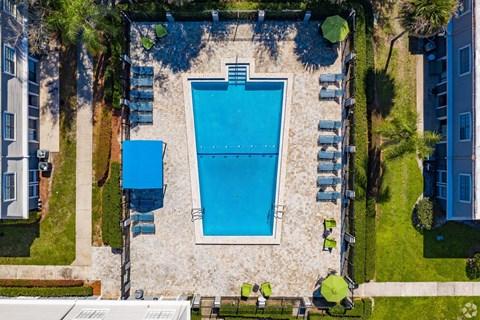 an aerial view of a swimming pool with chairs and umbrellas around it