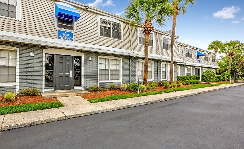 the front of a condo building with palm trees