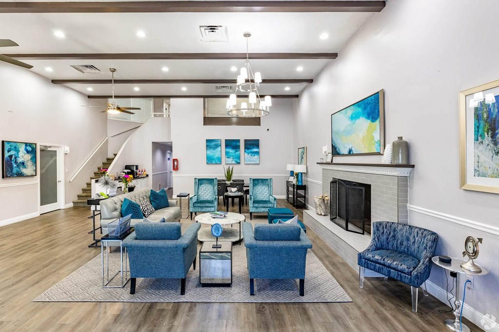 a living room with blue chairs and a fireplace  at The Park at Chesterfield Apartment Homes, Tampa, FL, 33617