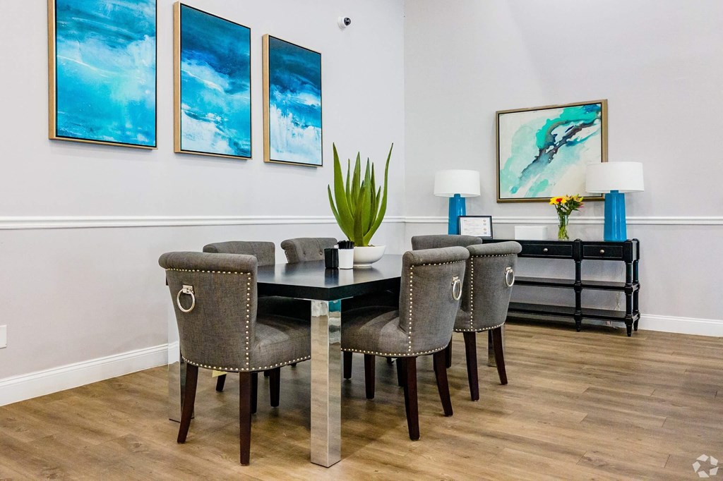 a dining room with a table and chairs and paintings on the wall  at The Park at Chesterfield Apartment Homes, Tampa