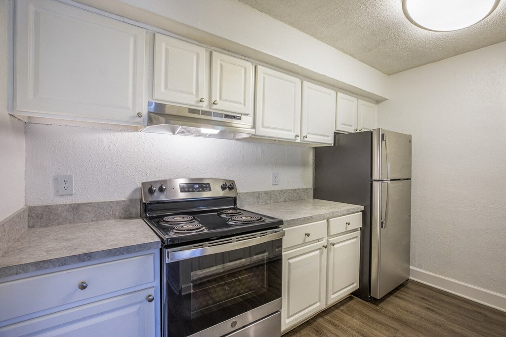A kitchen with white cabinets and a stainless steel refrigerator.
