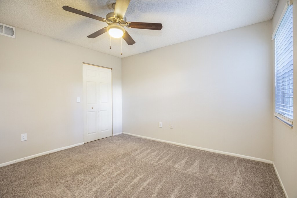 A room with a ceiling fan and carpeted floor.