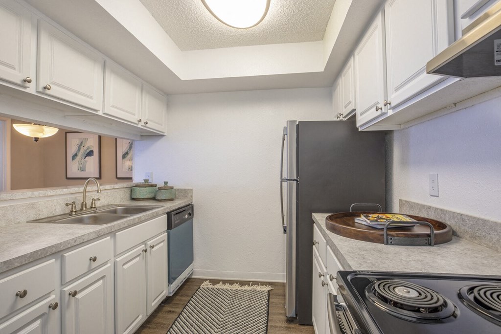 A kitchen with a black refrigerator and white cabinets.