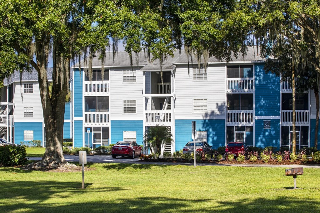 A blue and white apartment building with trees in front.
