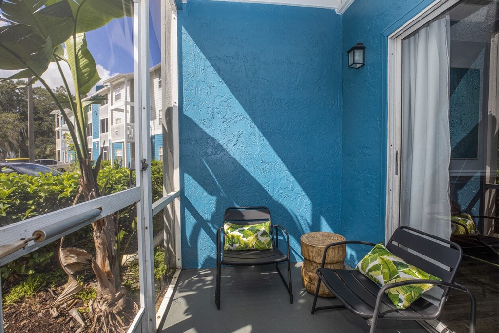 A blue wall with a white curtain and a black chair.