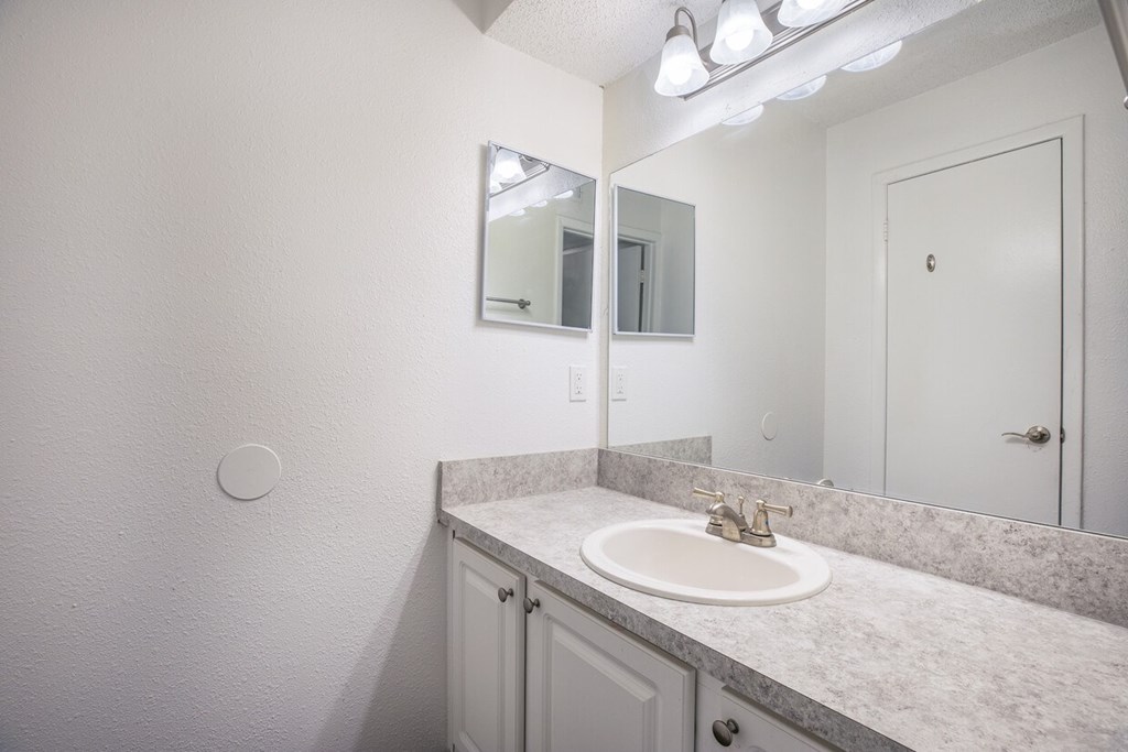 A bathroom with a sink, mirror, and light fixture.