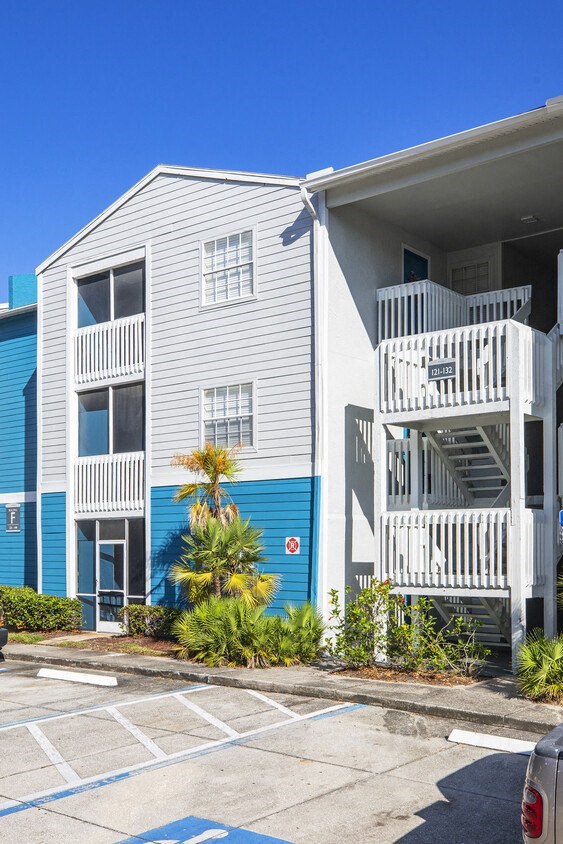A blue and white building with a parking lot in front.