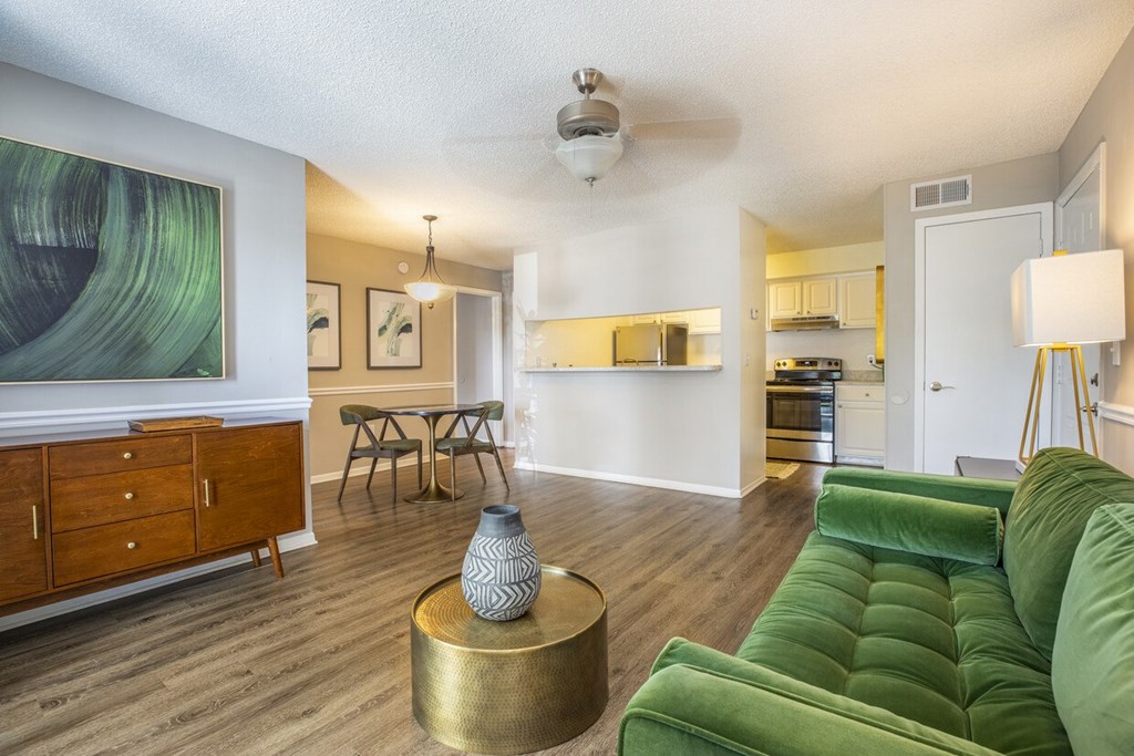 A living room with a green couch and a wooden floor.