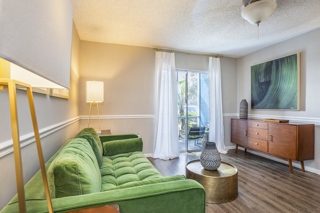 A living room with a green couch and a wooden cabinet.