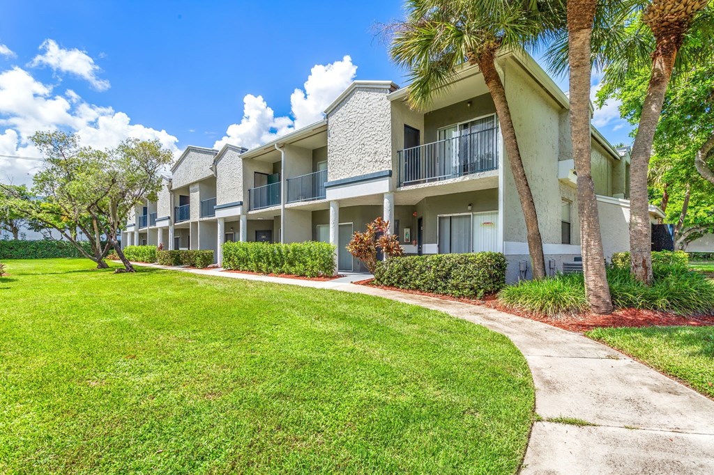 a sidewalk in front of an apartment building with palm trees at Waterford Park Apartment Homes, LLC, Lauderhill, FL 33319